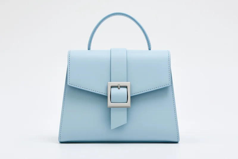 Light blue structured leather handbag with top handle and silver buckle on white background