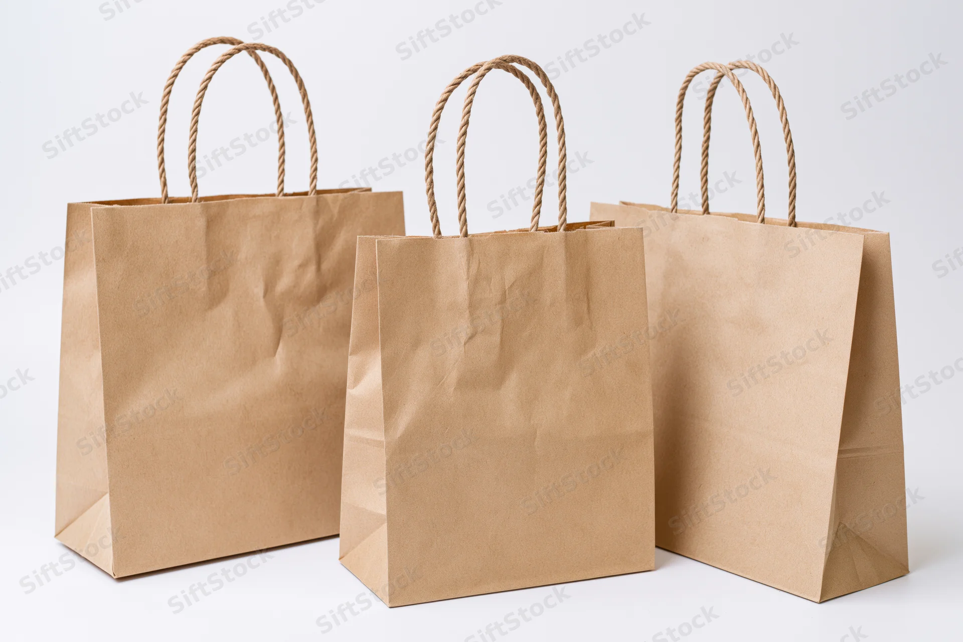 Three kraft paper shopping bags arranged side by side on white background