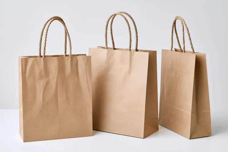Three kraft paper shopping bags arranged side by side on a white surface
