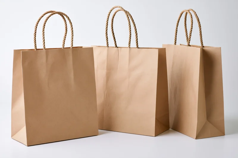 Three kraft paper shopping bags arranged side by side on white surface