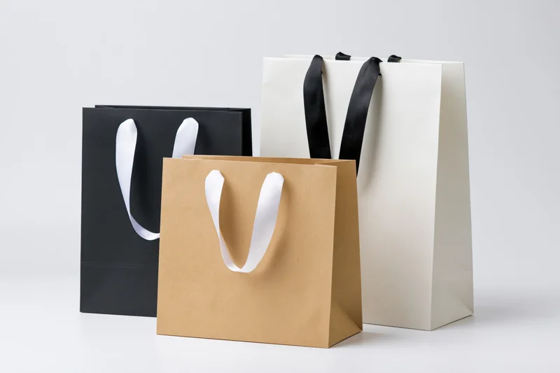 Three paper shopping bags arranged together on a plain white surface