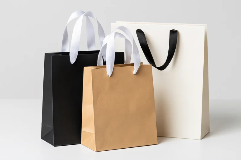 Three paper shopping bags arranged together on a plain white surface
