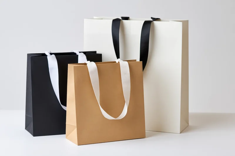 Three paper shopping bags arranged on a white surface