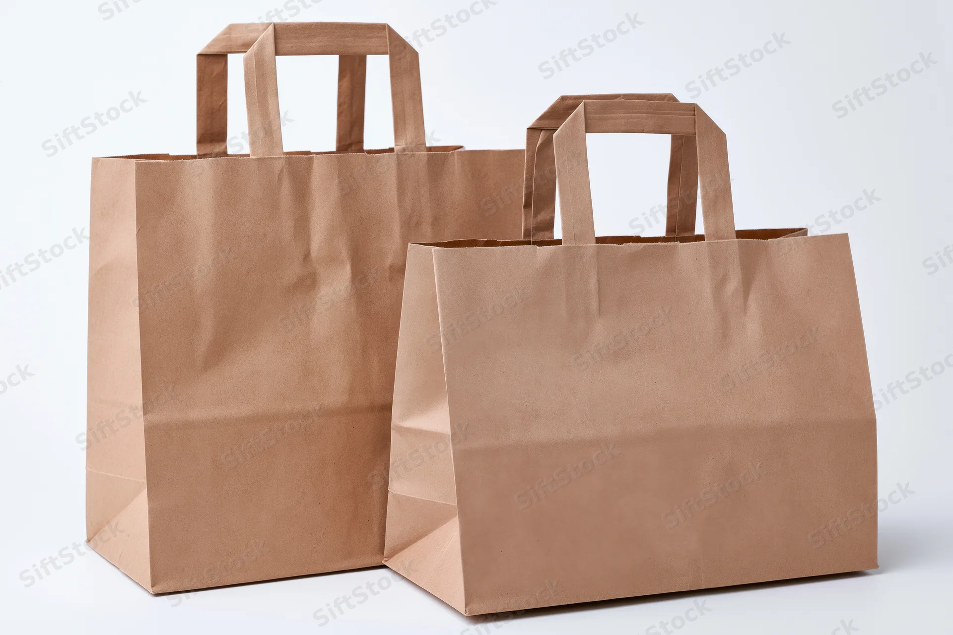 Two brown kraft paper shopping bags with flat handles on white background