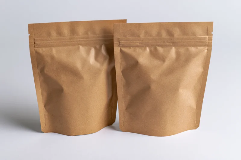 Two kraft brown mylar stand-up zipper pouches side by side on white background