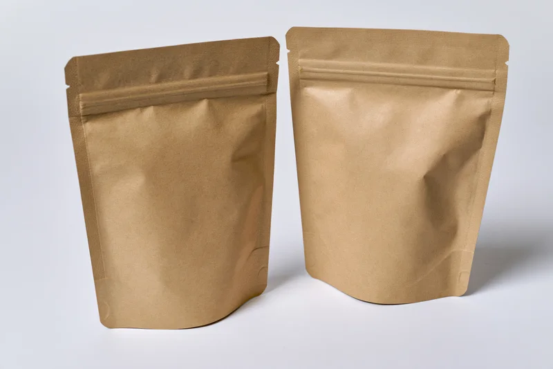Two kraft brown mylar stand-up zipper pouches side by side on white background