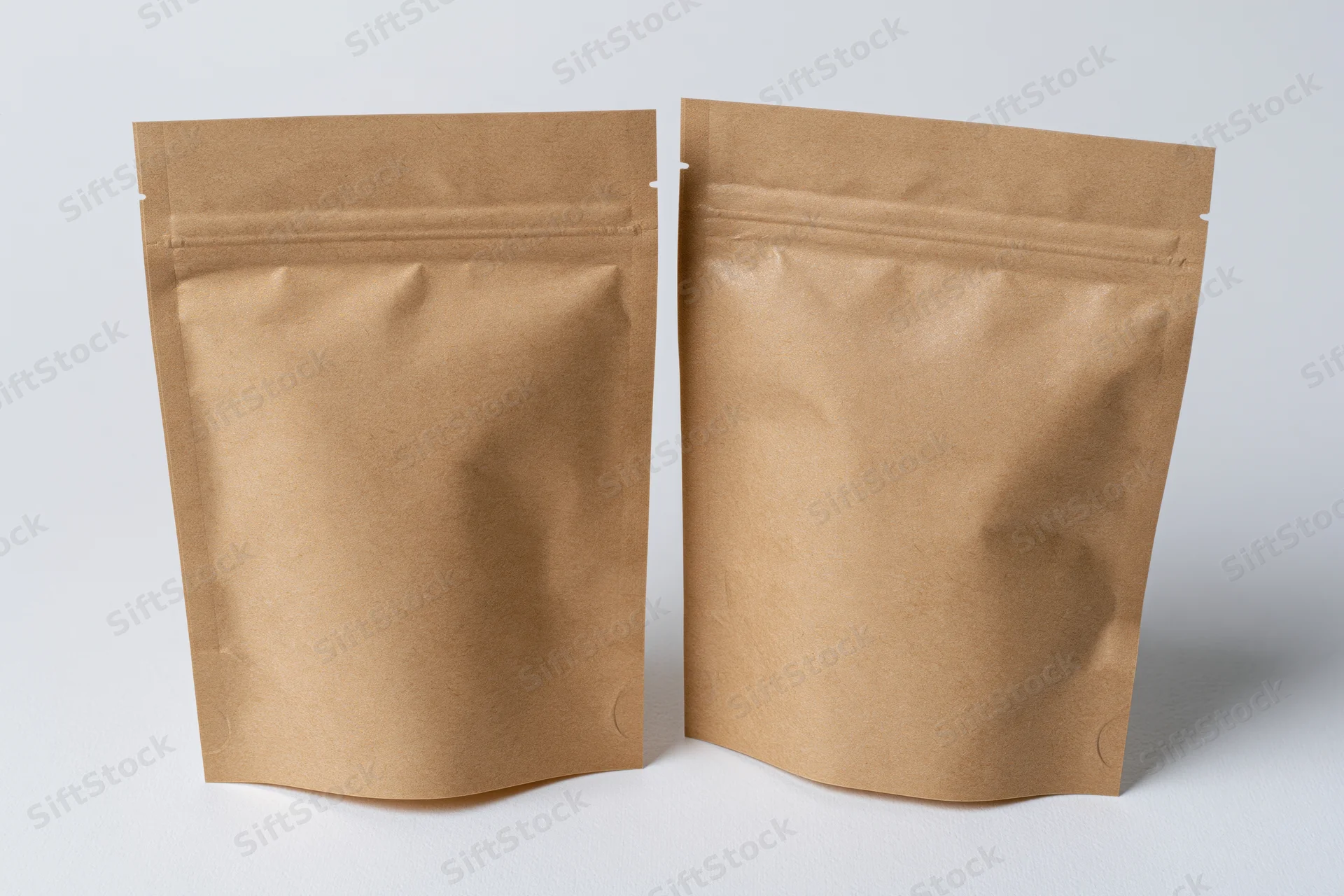 Two kraft brown mylar stand-up zipper pouches side by side on white background