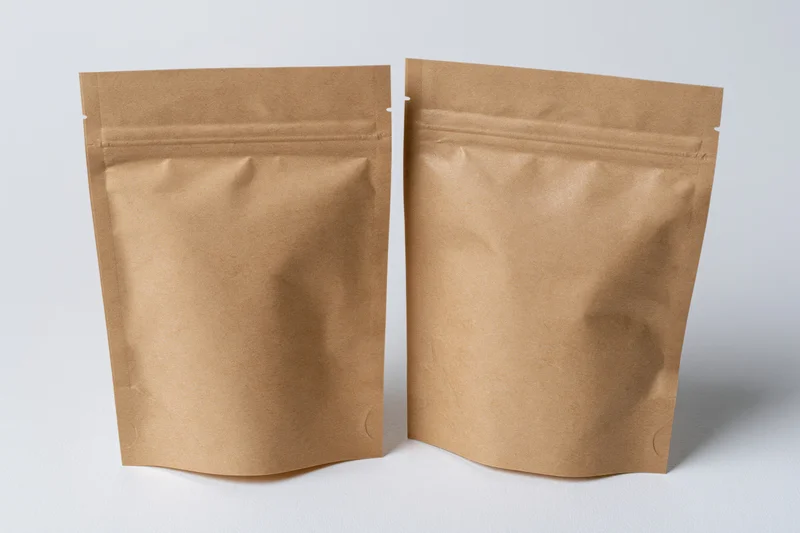 Two kraft brown mylar stand-up zipper pouches side by side on white background