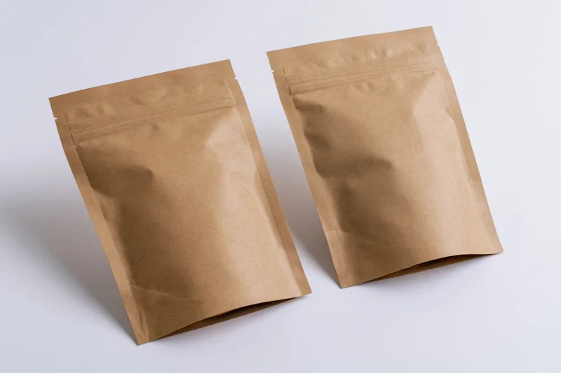 Two kraft brown mylar stand-up zipper pouches on white background