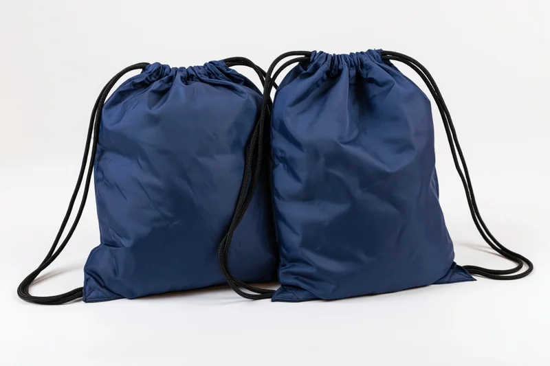 Two navy blue drawstring backpacks side by side on white background