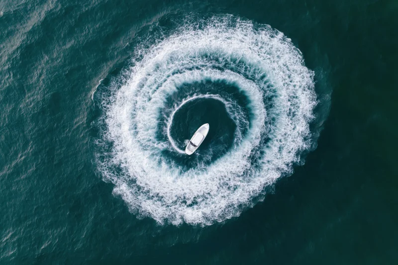 White motorboat turning in tight circular loops on open ocean water