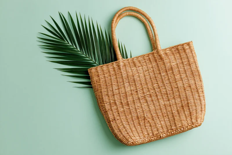 Woven straw tote bag with palm leaf on mint green background