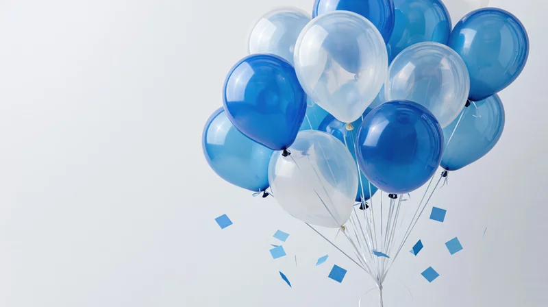 Cluster of blue and transparent helium balloons floating with blue confetti against white background