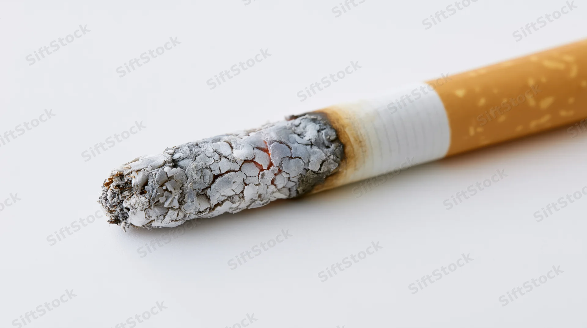 Lit cigarette with ash and ember in extreme close-up against white background