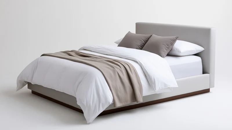 Modern upholstered platform bed with white bedding and grey pillows on plain white background