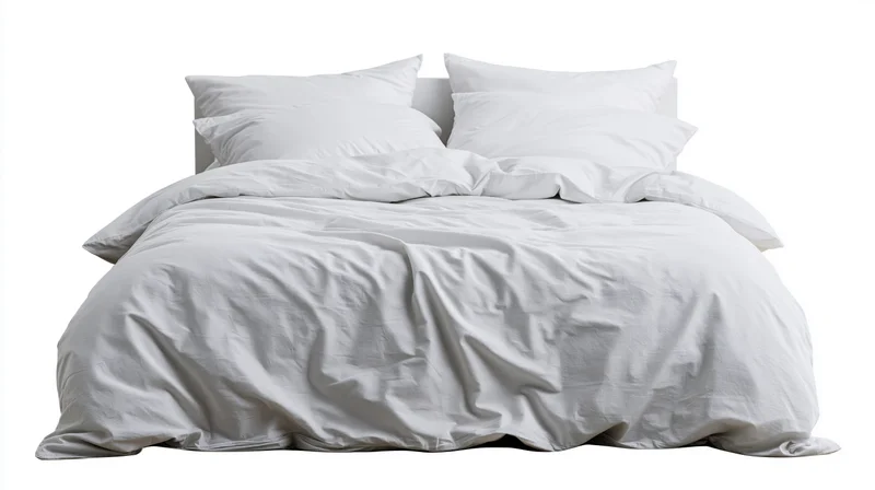 Unmade bed with white cotton duvet and four pillows on plain white background