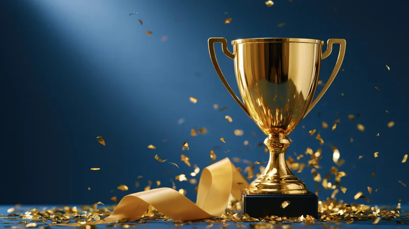 Golden trophy with ribbon and falling confetti on blue background