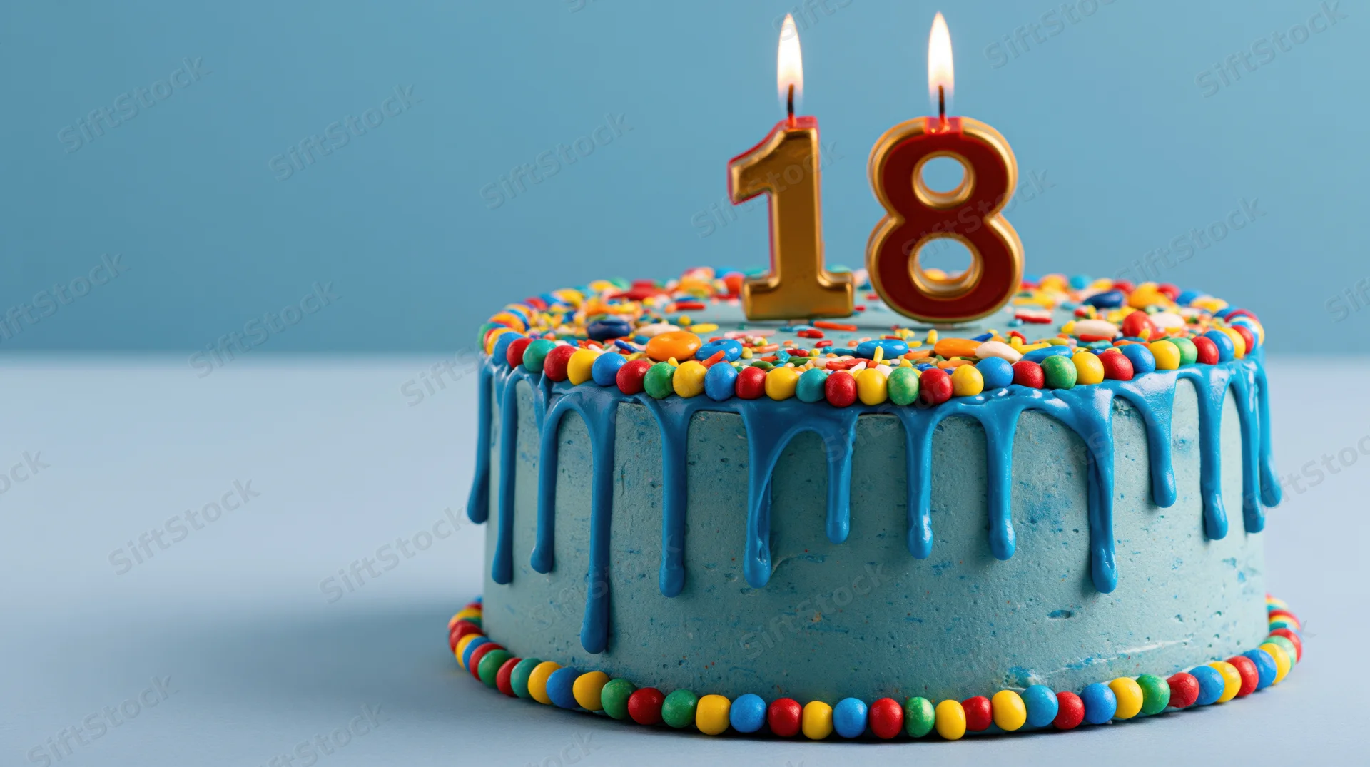 Blue frosted birthday cake with number 18 candles and colorful sprinkles on a plain surface
