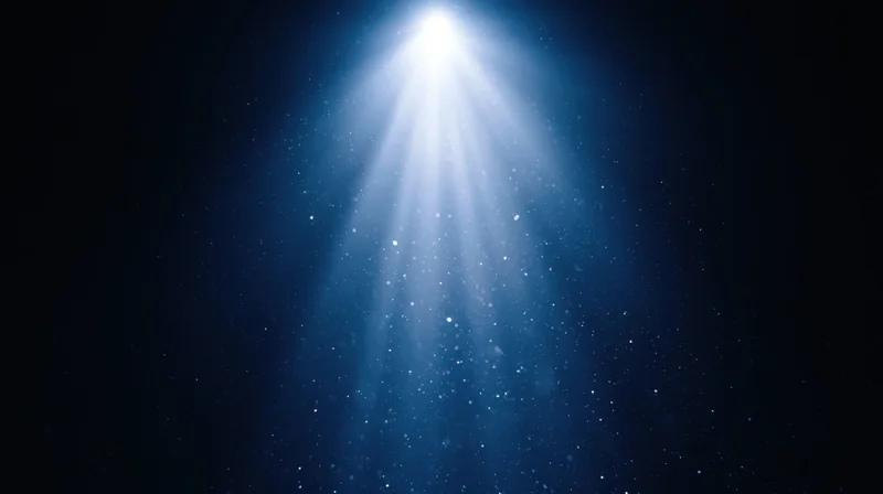 Bright spotlight beam shining downward through floating particles in dark blue space