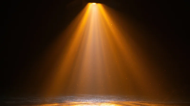 Golden spotlight beam shining downward on dark stage floor