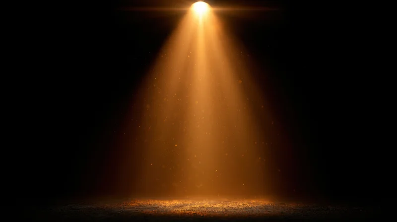 Golden spotlight beam shining downward on dark stage floor