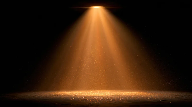 Golden spotlight beam shining downward on a dark stage floor