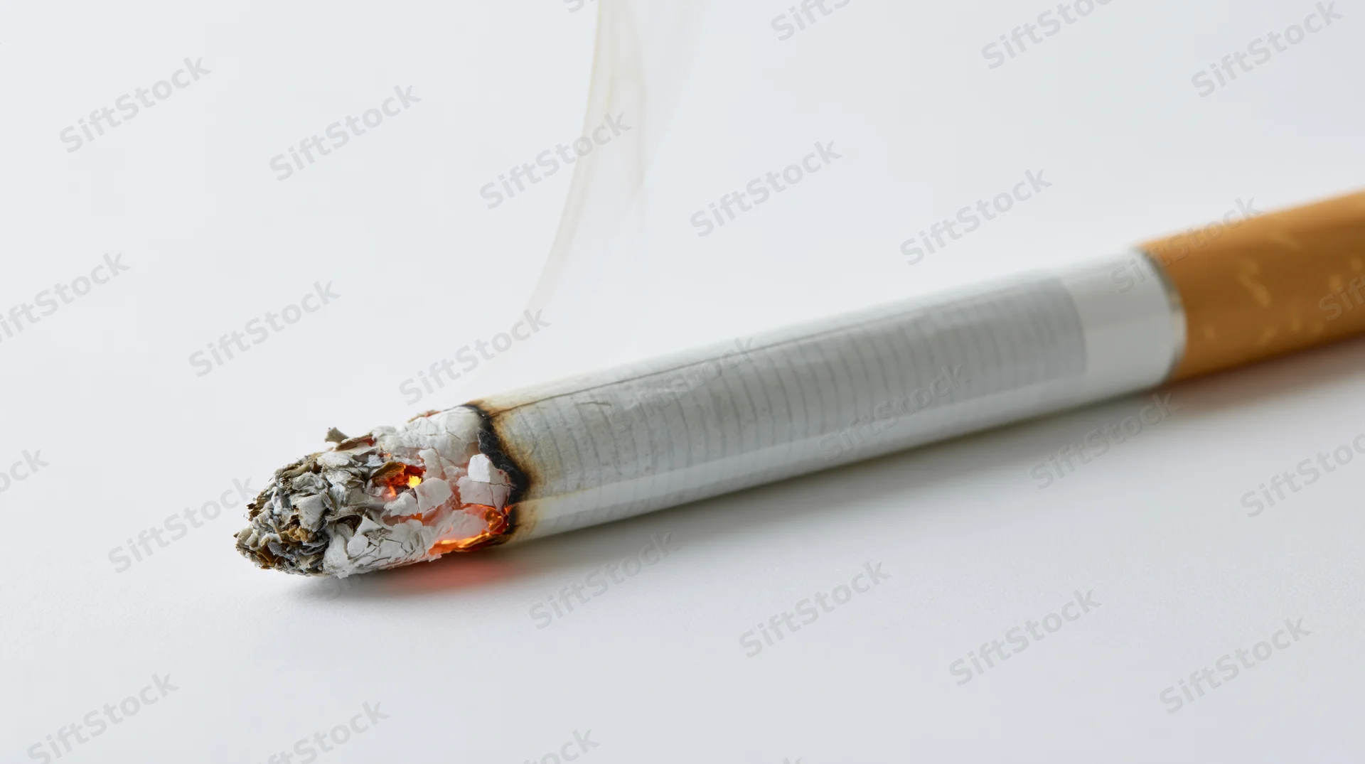 Lit cigarette burning with smoke and ash on white background