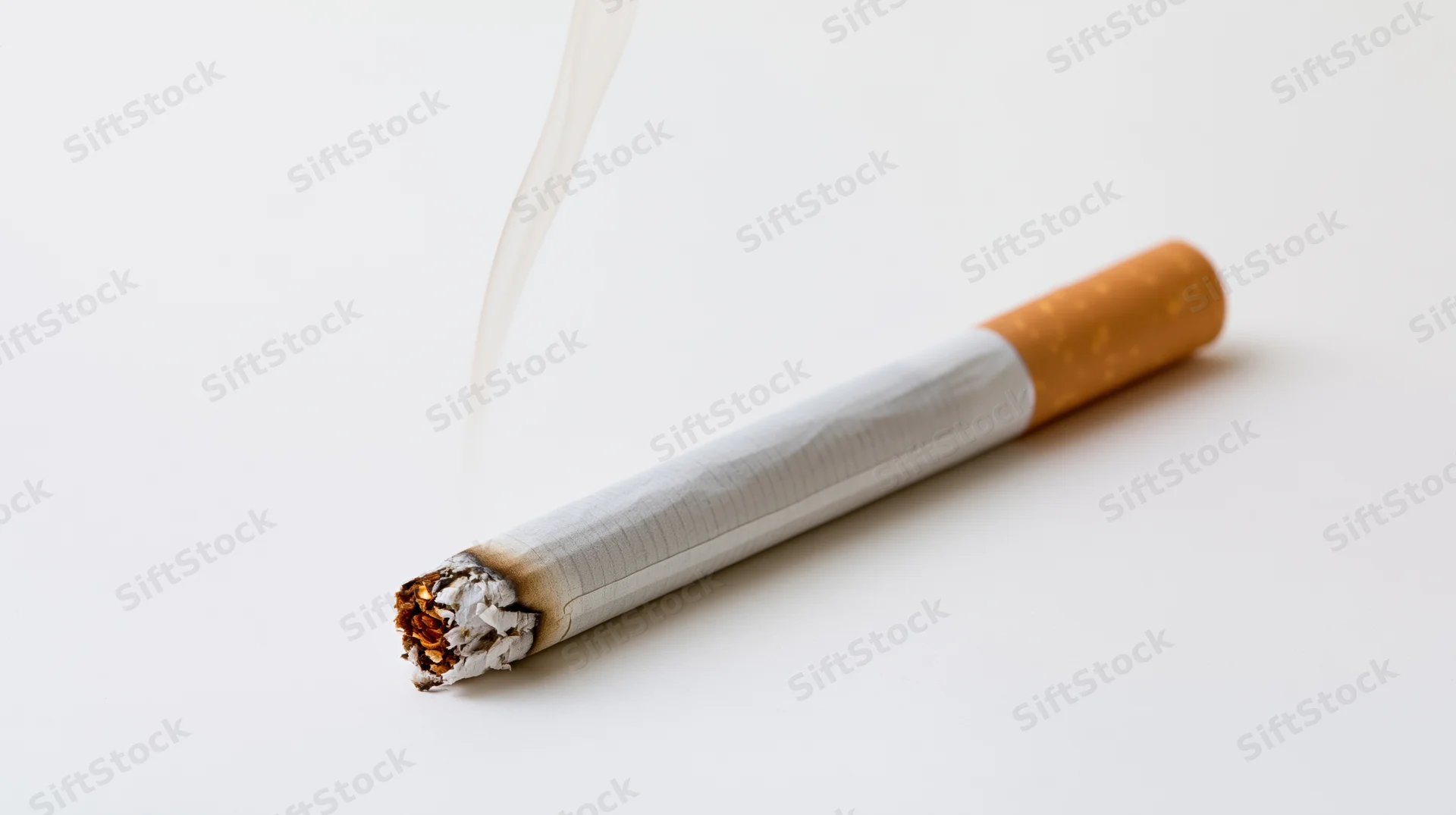 Lit cigarette burning with smoke rising on white background