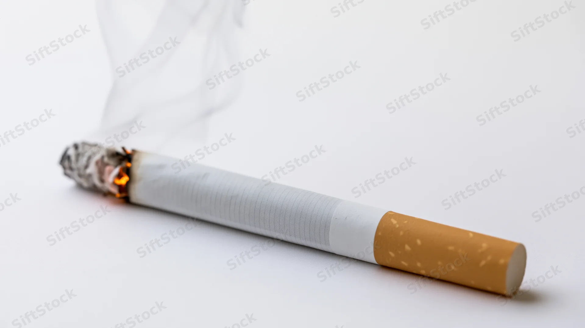 Lit cigarette burning with smoke rising on white background