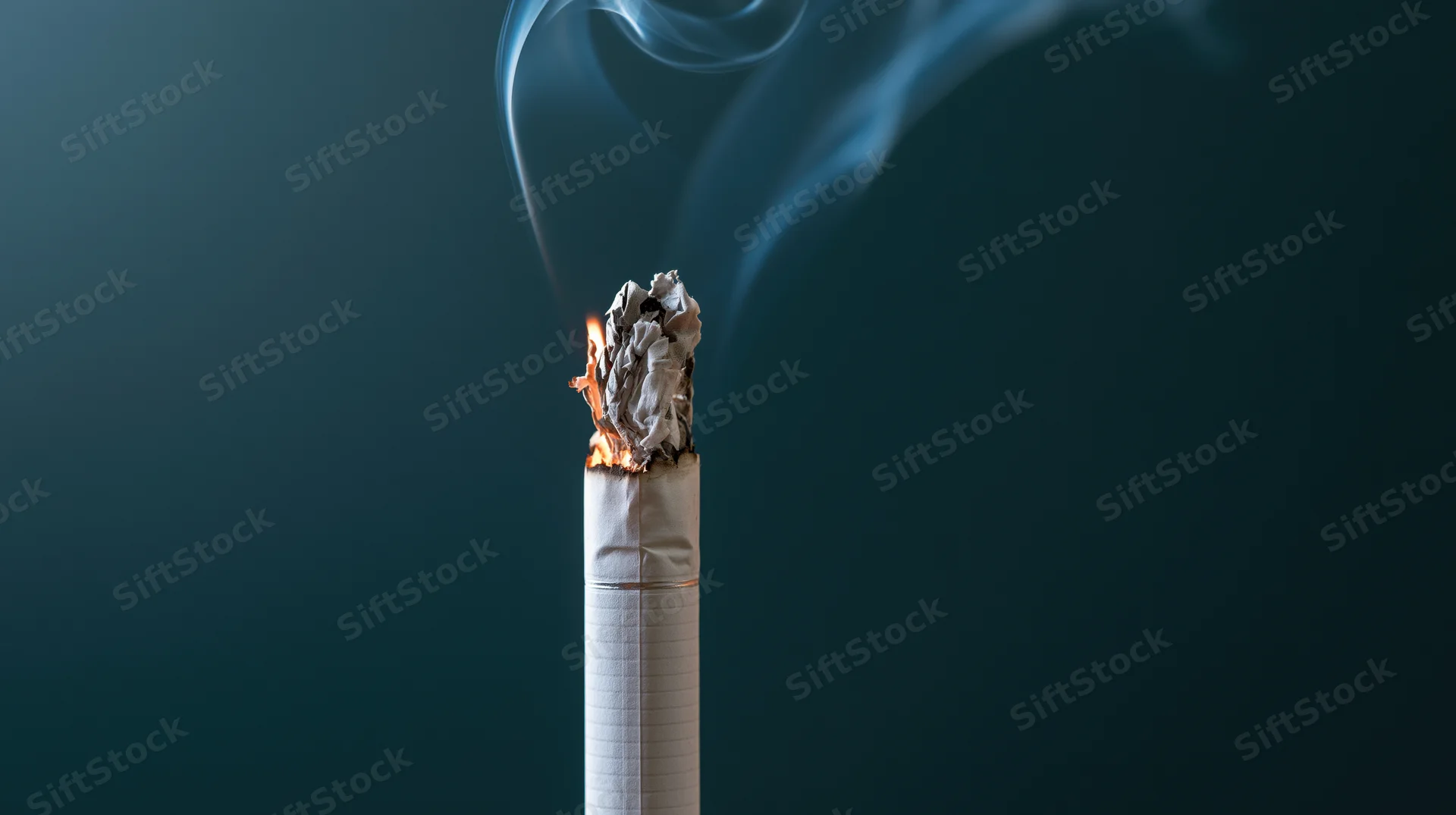 Lit cigarette burning upright with glowing ember and rising smoke against dark blue background