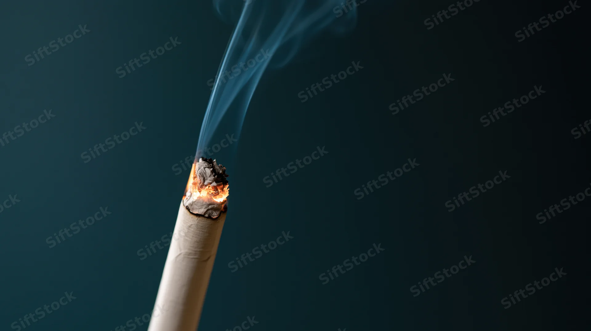 Lit cigarette with glowing ember and rising smoke against dark background