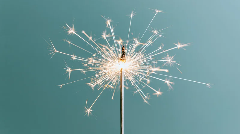 Lit sparkler radiating white sparks against teal background