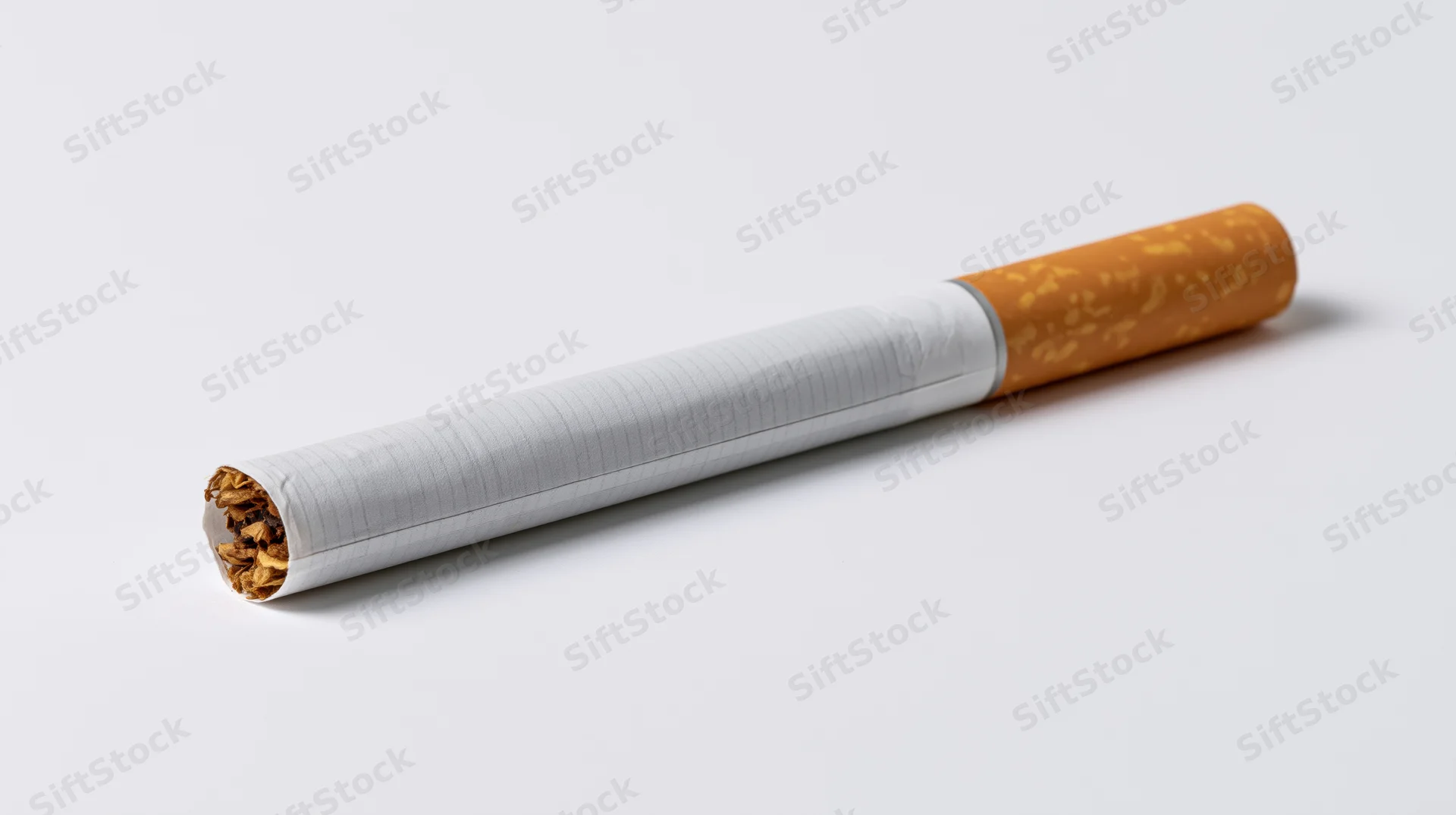 Unlit cigarette with orange filter lying diagonally on white background
