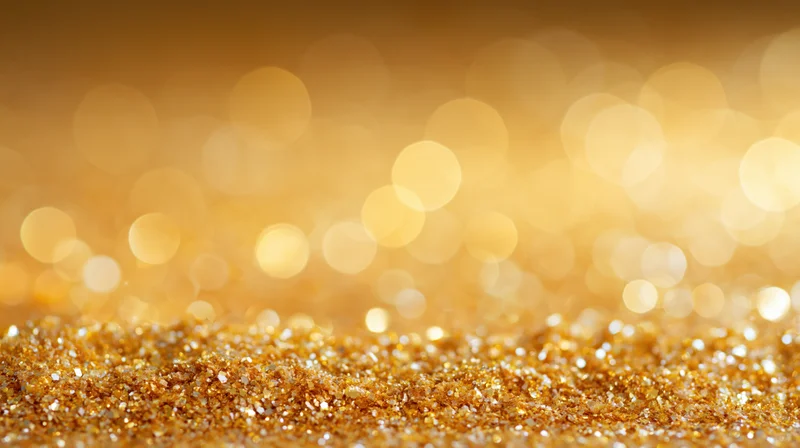 Scattered gold glitter particles on a soft glowing background with bokeh lights