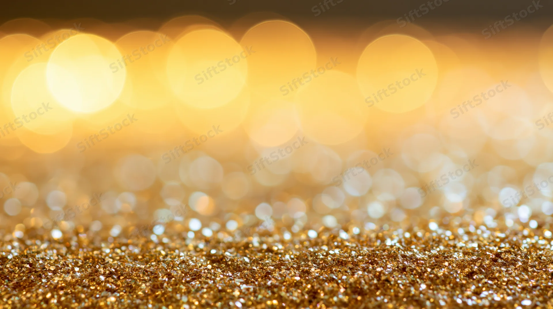 Scattered gold glitter particles with bokeh lights in the background