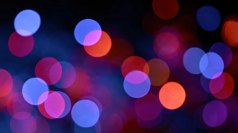 Abstract bokeh background with out-of-focus colorful light orbs in dark setting