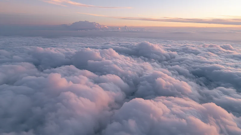Aerial view above a vast sea of billowing cumulus clouds at sunrise