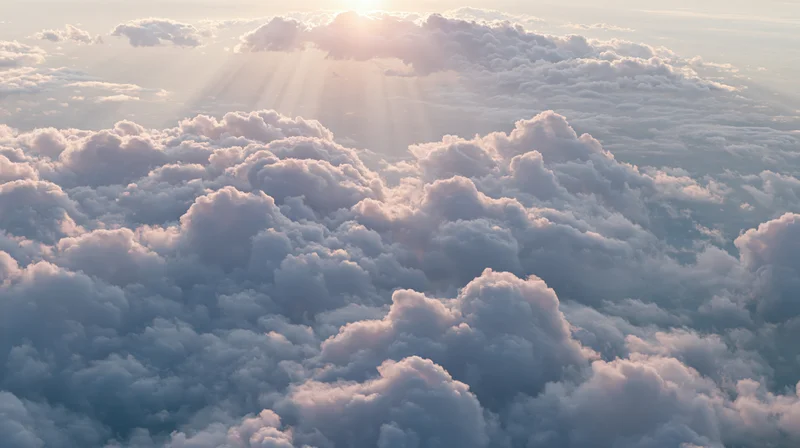 Aerial view of vast cloudscape with sun rays above horizon