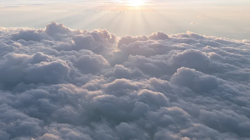 Aerial view of a vast cloudscape at sunrise with sun rays above the horizon