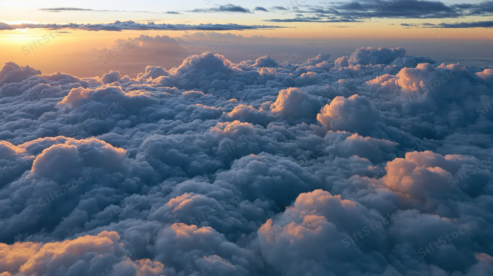 Aerial view of dense cumulus clouds at sunset above the horizon