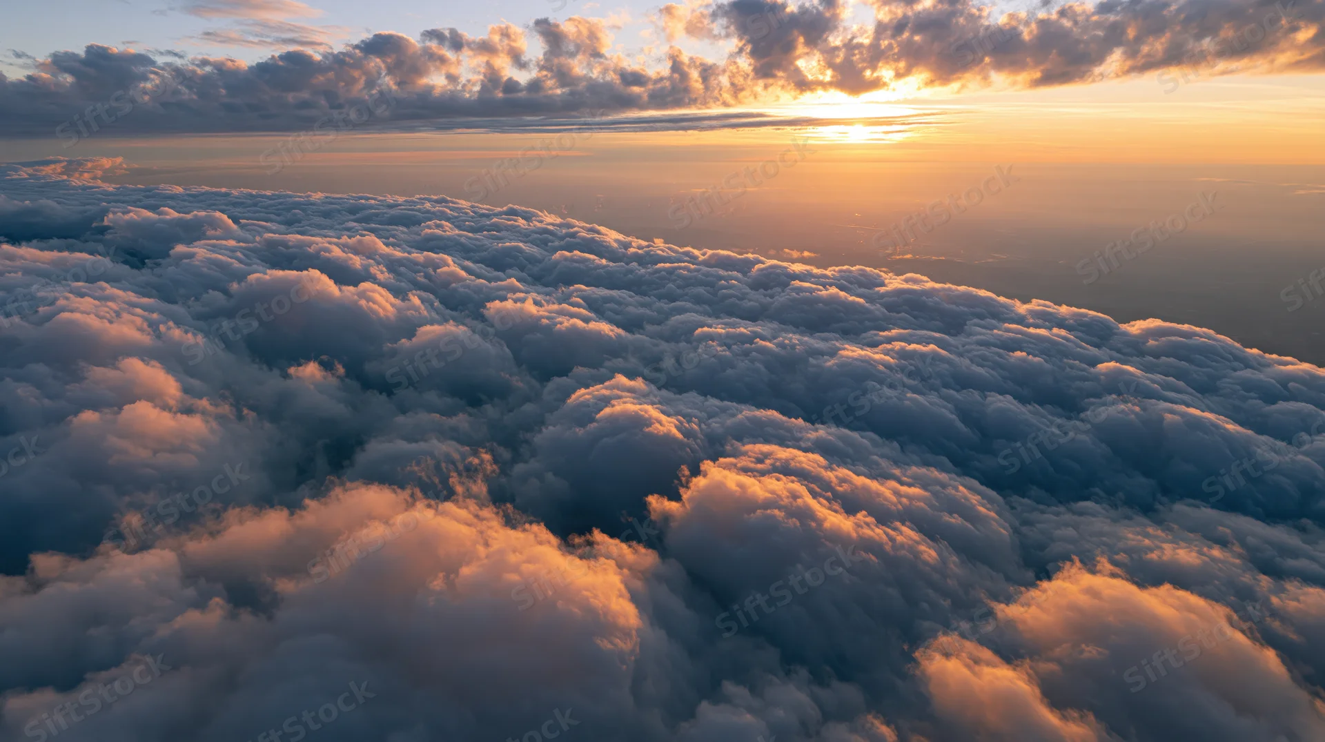 Aerial view of dense cumulus clouds at sunset above the horizon