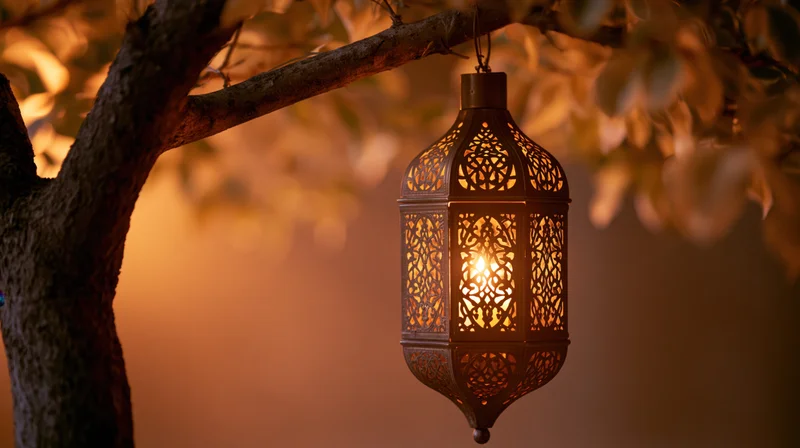 Ornate brass arabic lantern hanging from tree branch glowing in twilight