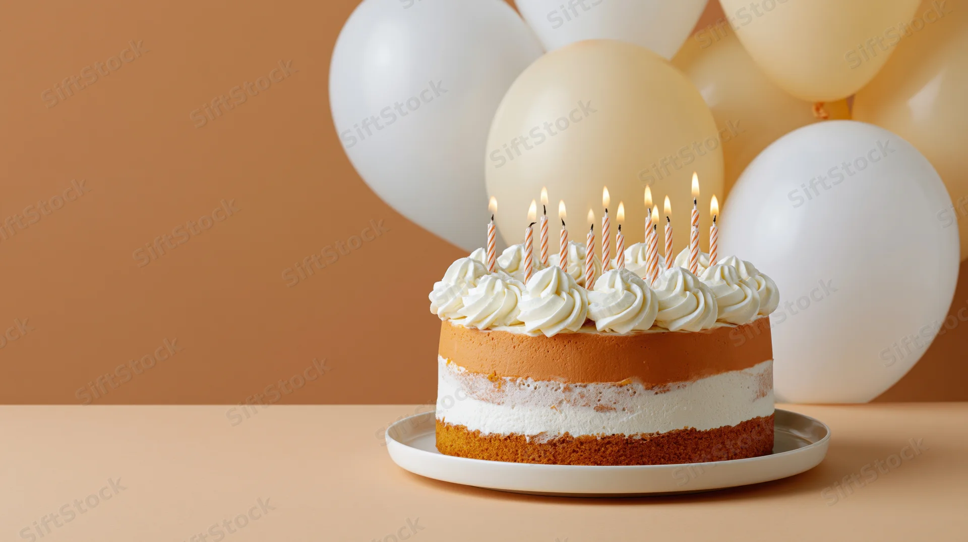 Birthday cake with lit candles on a white plate in front of balloons on a warm-toned background