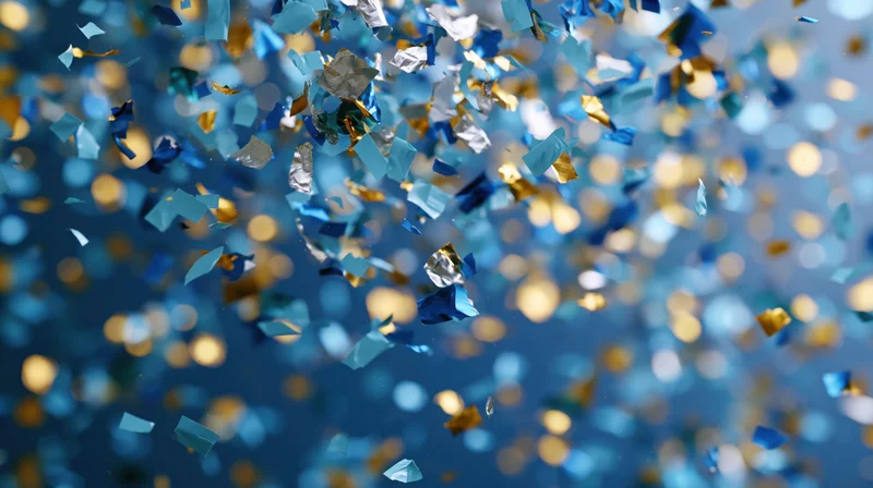 Blue and gold metallic confetti suspended mid-fall against a blurred bokeh background