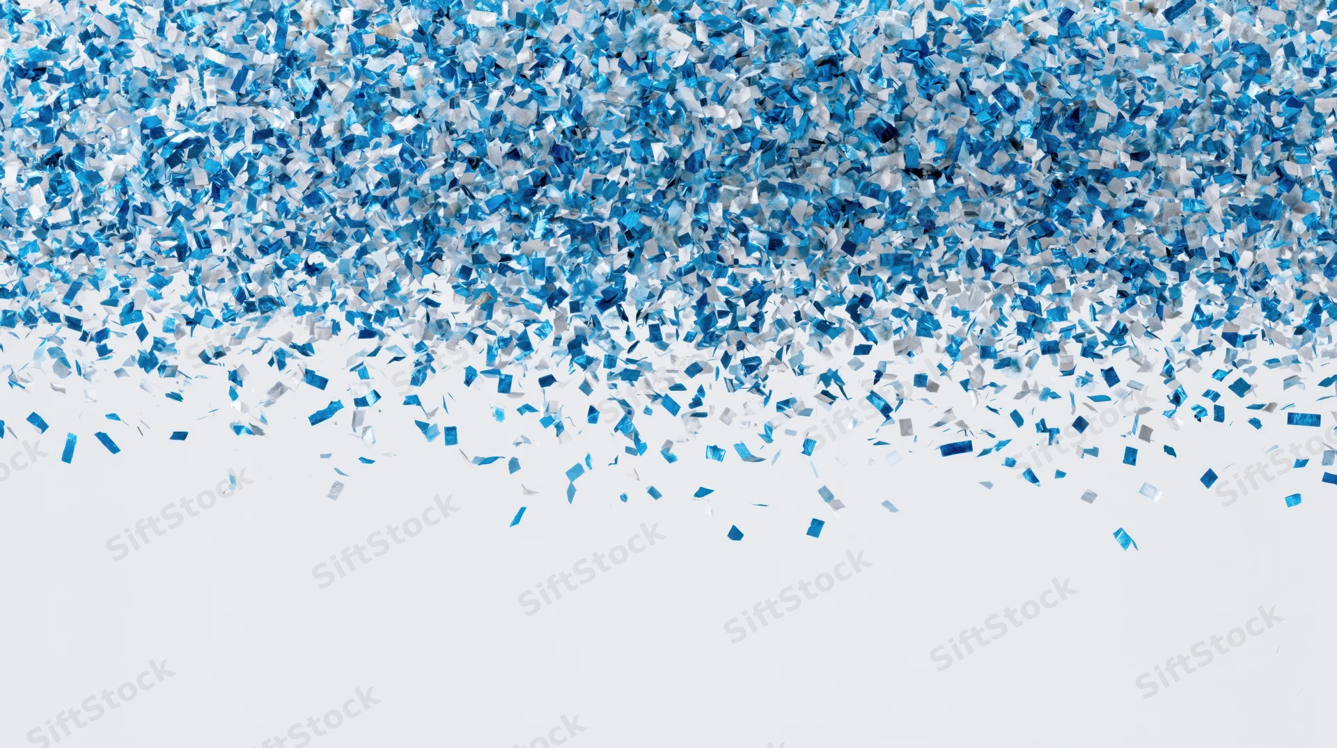 Blue metallic confetti pieces falling and scattering mid-air against white background with copyspace below
