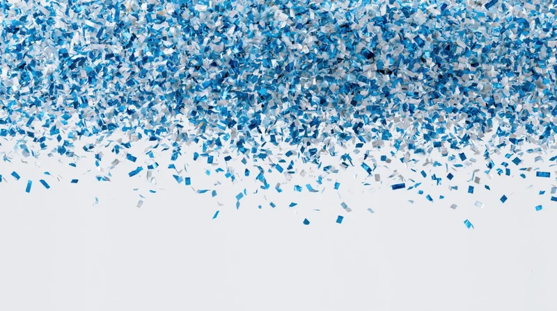 Blue metallic confetti pieces falling and scattering mid-air against white background with copyspace below