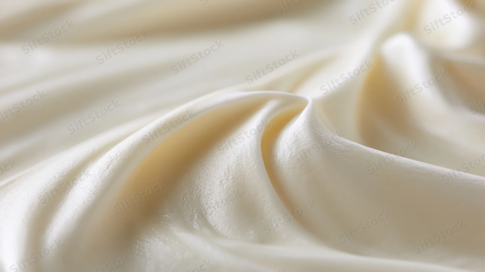 Close-up of smooth white cream surface with soft swirls and glossy texture