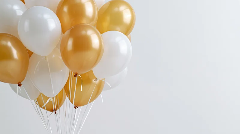 Cluster of white and gold helium balloons floating against a plain background with copyspace