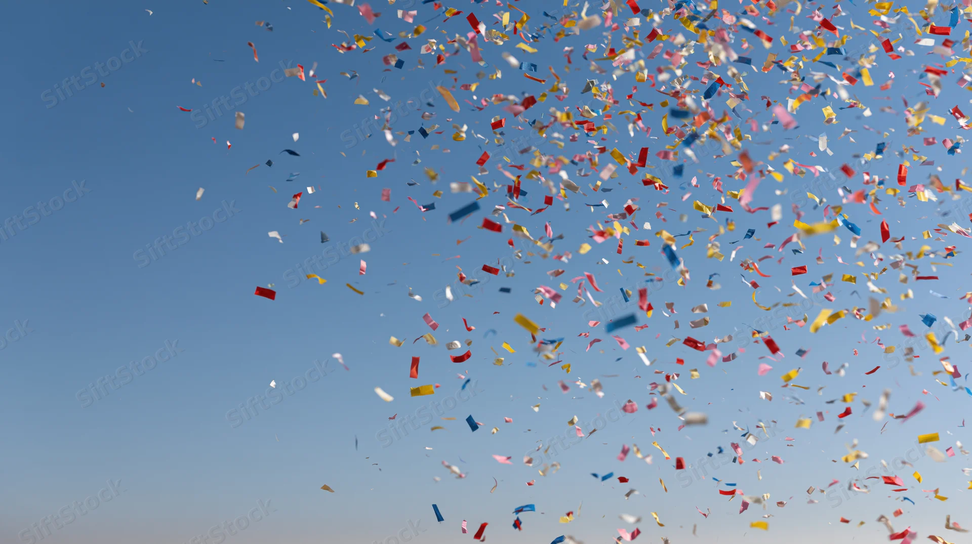 Colorful confetti and paper streamers exploding upward into the sky