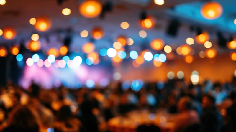 Blurred interior of a crowded banquet hall with warm and cool lights glowing overhead
